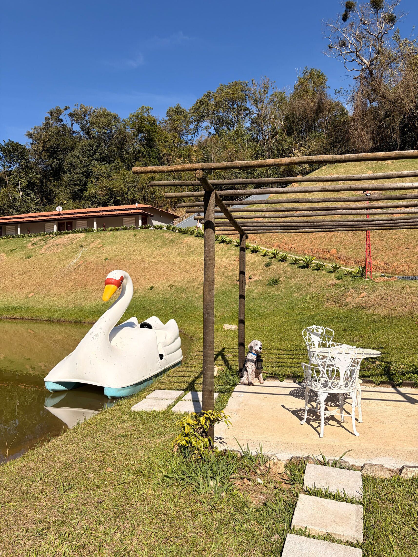 Un bote con forma de cisne sobre aguas tranquilas, un pabellón y una silla blanca.