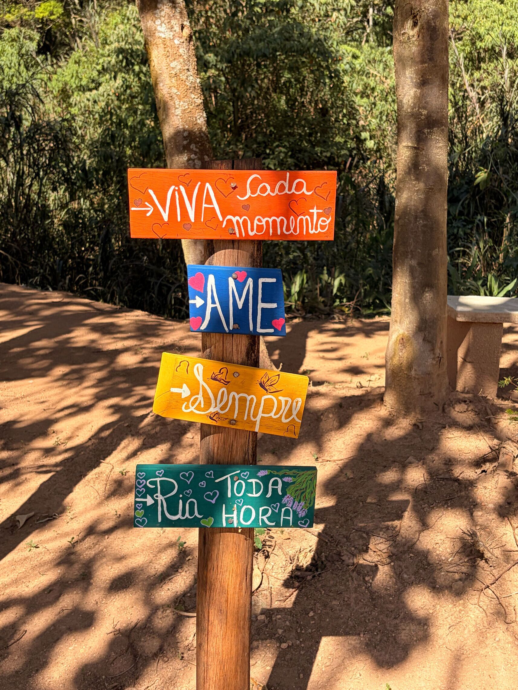 A wooden signpost with multiple directional signs, each with a different message.
