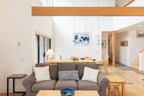 Ein modernes Wohnzimmer mit Sofa, Esstisch und Blick zur Küche.