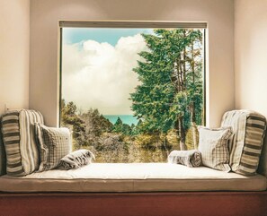 Ein Fensterplatz mit Blick auf einen Wald und ein Gewässer.