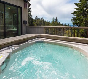 A hot tub with a wooden deck and a glass wall, surrounded by trees and a clear sky. - Sea Ridge (TOT ID #2175): 3  BR, 3  BA House in The Sea Ranch, Sleeps 6 (The Sea Ranch)
