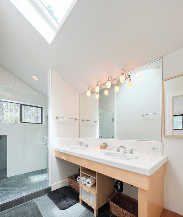 A modern bathroom with a large mirror, two sinks, and a skylight. - Sea Ridge (TOT ID #2175): 3 BR, 3 BA House in The Sea Ranch, Sleeps 6 (The Sea Ranch)