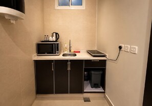 A compact kitchenette with a microwave, sink, and storage cabinet.
