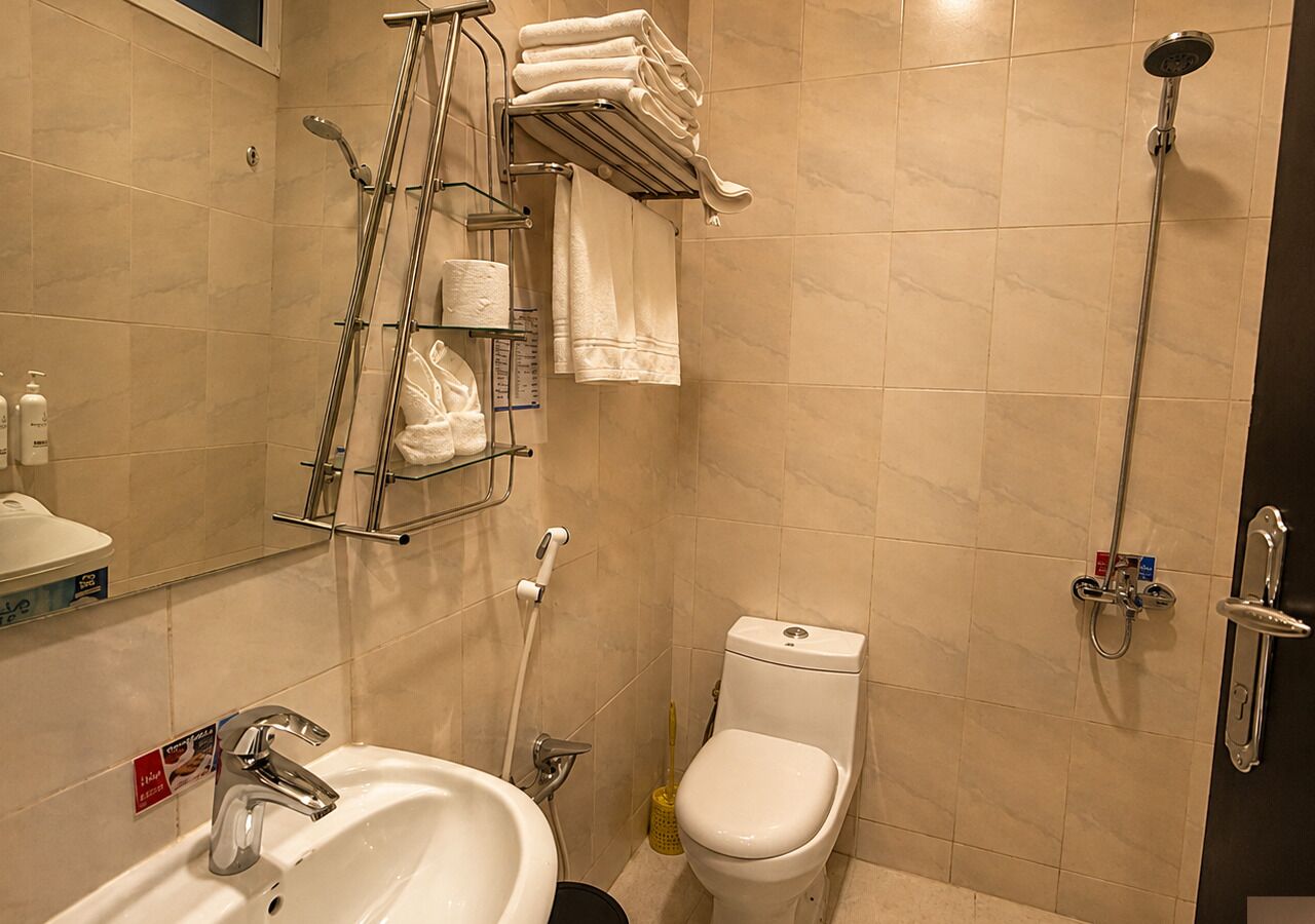 A bathroom with a sink, toilet, shower, and towel rack.