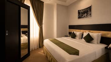 A hotel room with a large bed, a wardrobe, a painting on the wall, and a curtain.