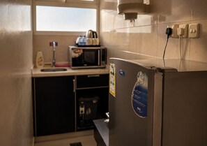 A compact kitchenette with a refrigerator, microwave, and a small sink.