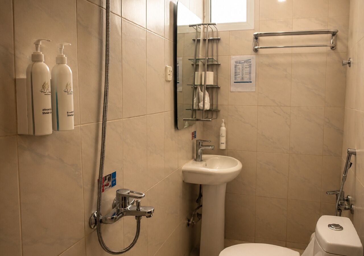 A bathroom with a shower, sink, and toilet. There are toiletries on the wall and a towel rack.