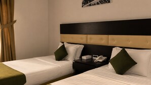 Habitación de hotel con dos camas, una mesita de noche y un teléfono.