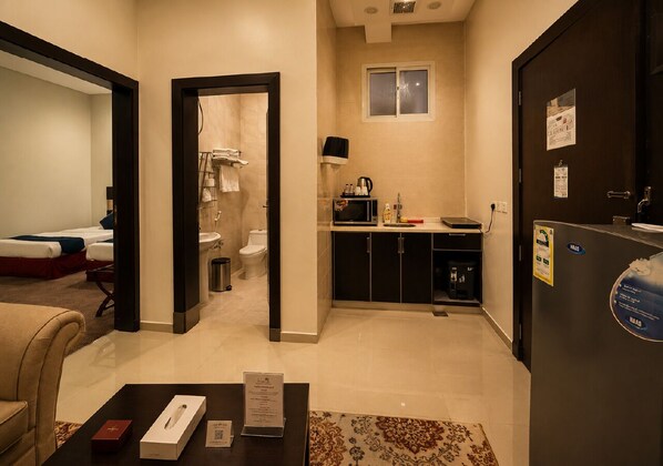 A hotel room with a living area, a kitchenette, and a bathroom.