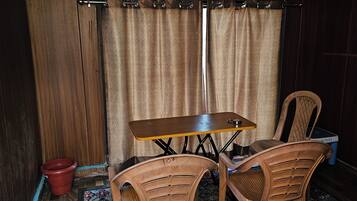 A room with a wooden table and chairs, a patterned rug, and a curtain.