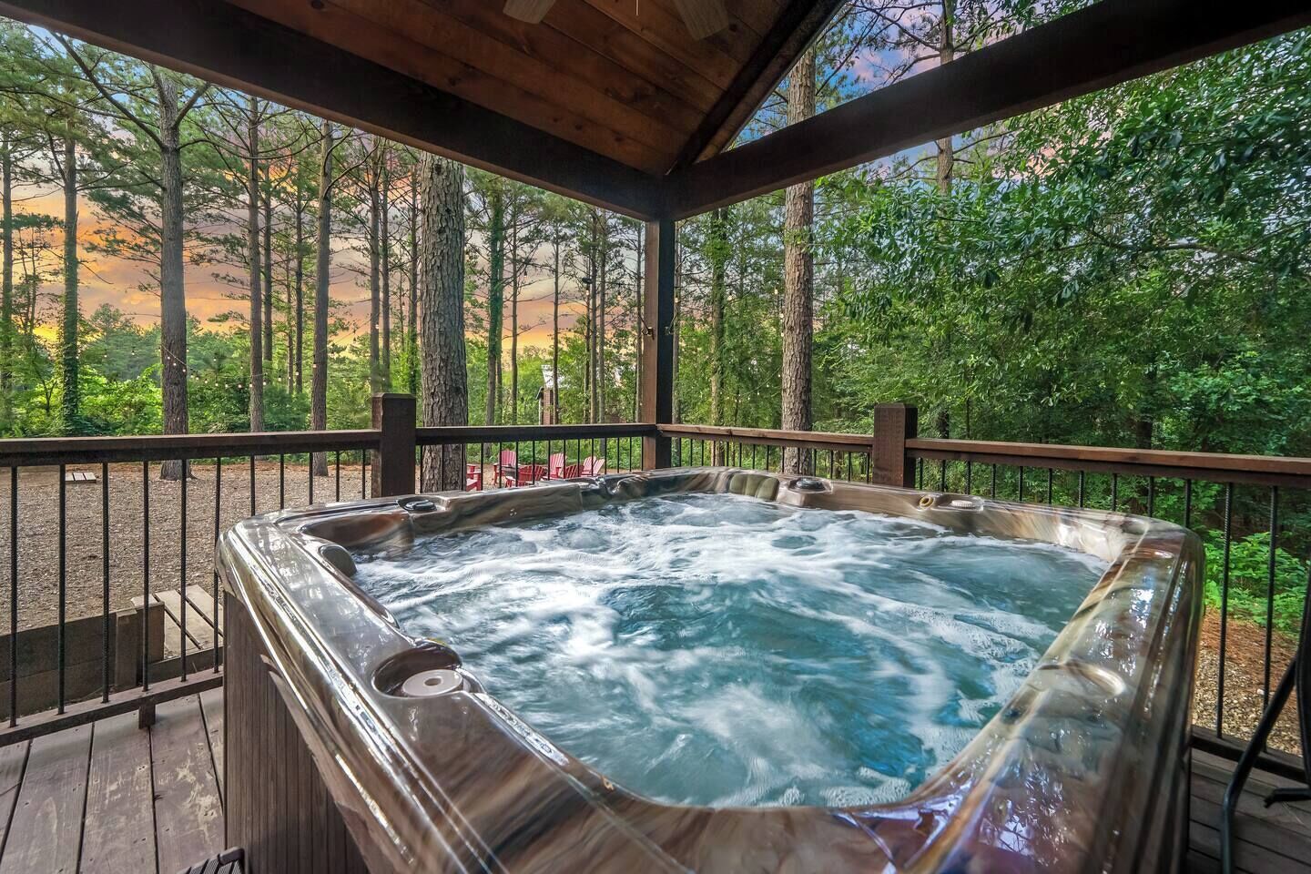 Ein Whirlpool auf einer Holzterrasse mit Blick auf einen Wald.