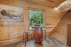 Ein Holzinterieur mit einem runden Barbereich, zwei Hockern und einem Bisonsbild.