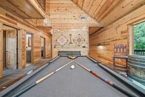 A pool table in a wooden cabin with a view of trees outside. - Dog-Friendly Lodge for 18 with 4 King Suites (Broken Bow)