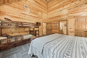 Una habitación de cabaña de madera con literas, una cama individual y un pequeño aparador.