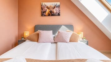 Ein Schlafzimmer mit einem Bett, Kissen, einem Nachttisch, einer Lampe und einem Wandbild.