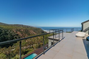 A rooftop terrace with a pool, overlooking a coastal landscape.