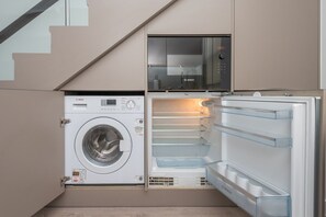 A compact kitchen with a built-in washing machine and a refrigerator. - Fulham Duplex Near Parsons Green Station (London)