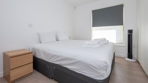 Ein schlicht eingerichtetes Schlafzimmer mit Bett, Nachttisch und einem Heizkörper.