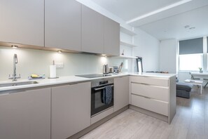 A modern kitchen with a built-in oven, a sink, and a countertop. - Fulham Duplex Near Parsons Green Station (London)