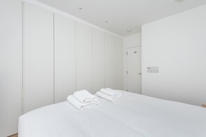 A hotel room with a large bed, a wardrobe, and a wall socket. - Fulham Duplex Near Parsons Green Station (London)