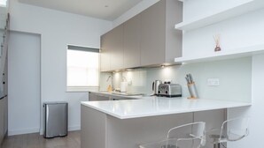 Eine moderne Küche mit einer zentralen Kochinsel, Barhocker und einem Edelstahl-Kühlschrank.