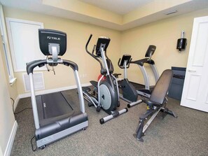 Un gimnasio con cintas de correr, elípticas y una bicicleta estática.