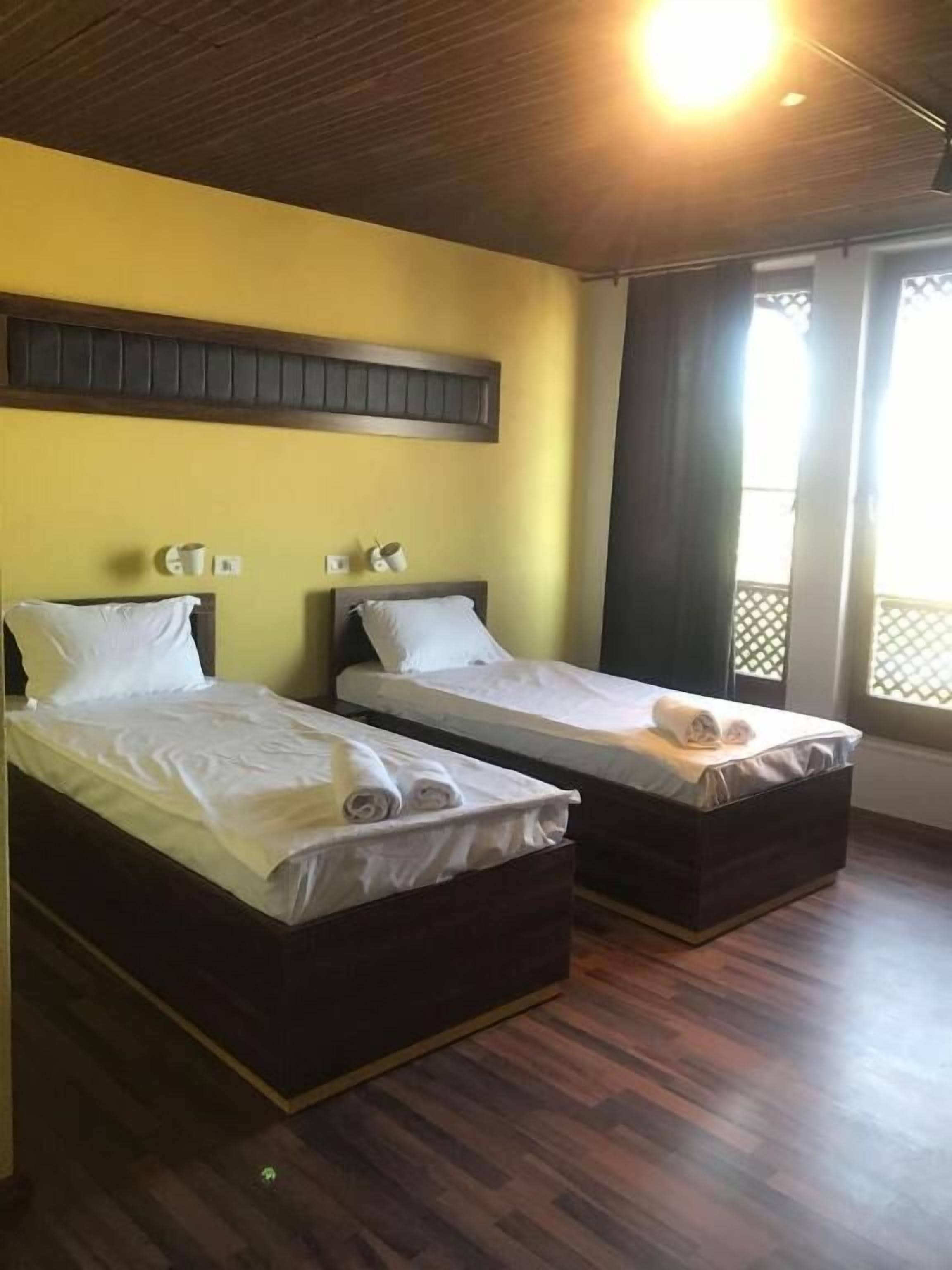 Quarto com duas camas, piso de madeira e janela com vista.