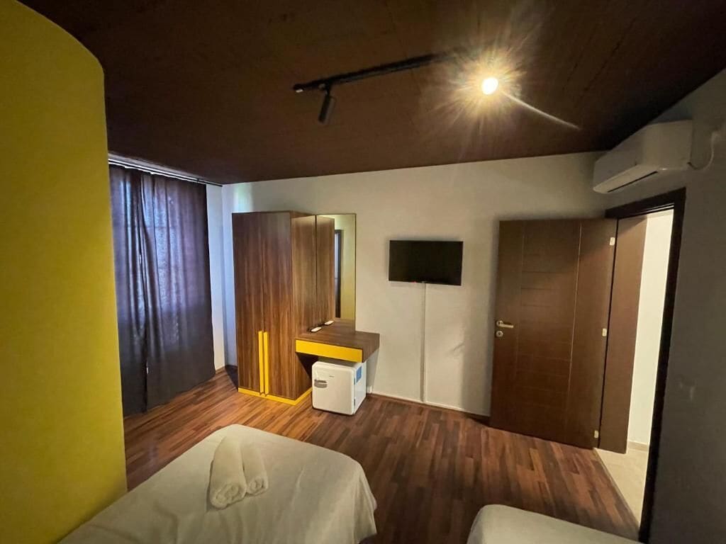 A hotel room with a bed, a desk, a wardrobe, and a television.