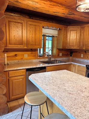 A kitchen with wooden cabinets, granite countertops, a stainless steel sink, and a dishwasher.