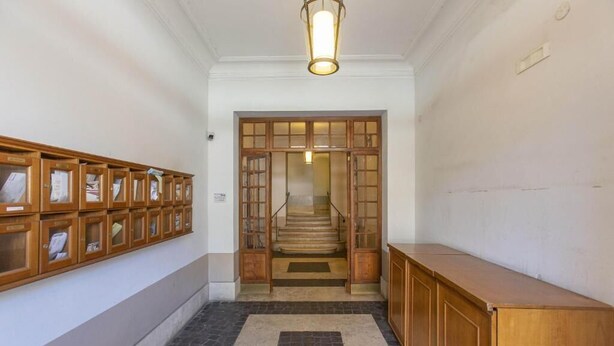 A hallway with a wooden cabinet, a tiled floor, and a staircase leading to another room. - SweetHouse Campo de Fiori (Roma)