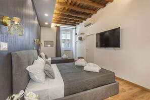 Ein Hotelzimmer mit zwei Betten, einem Fernseher und einer Holzbalkendecke.