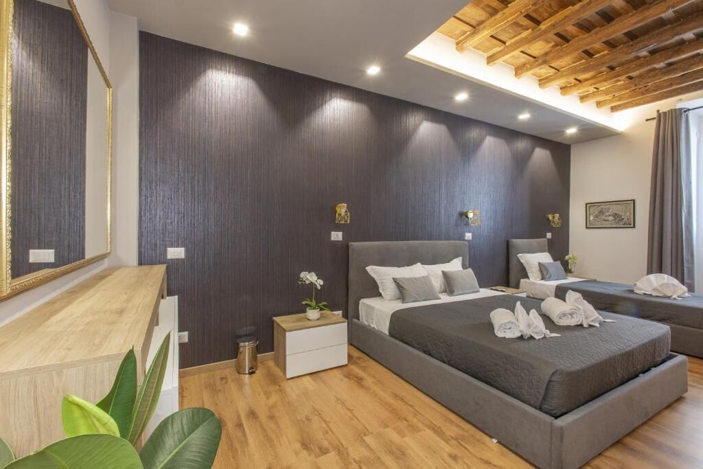 Ein modernes Hotelzimmer mit einem großen Bett, einem kleineren Bett, einem Schreibtisch und einem Spiegel.