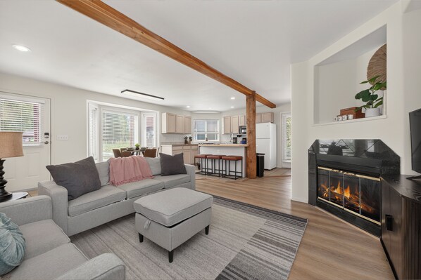 A modern living room with a grey sofa, ottoman, and a fireplace.