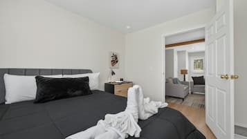 Ein Schlafzimmer mit Bett, Nachttisch, Lampe und einer Tür zu einem anderen Raum.