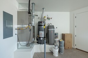 Ein Zimmer mit Warmwasserbereiter, einer Heizungsanlage und einer Tür zum Heizungsraum.