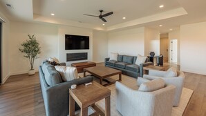 A spacious living room with a flat-screen TV, a ceiling fan, and a large potted plant. - The Approach Shot: 4  BR, 4  BA House in St. George, Sleeps 10 (St. George)