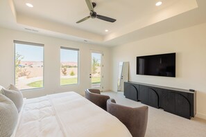 Un dormitorio moderno con una cama grande, un televisor de pantalla plana y un ventilador de techo.