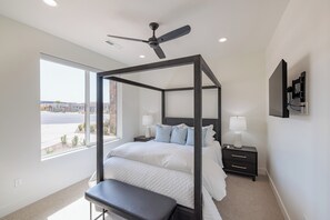 Ein Schlafzimmer mit einem Himmelbett, Nachttischlampen, einer Bank und einem Deckenventilator.