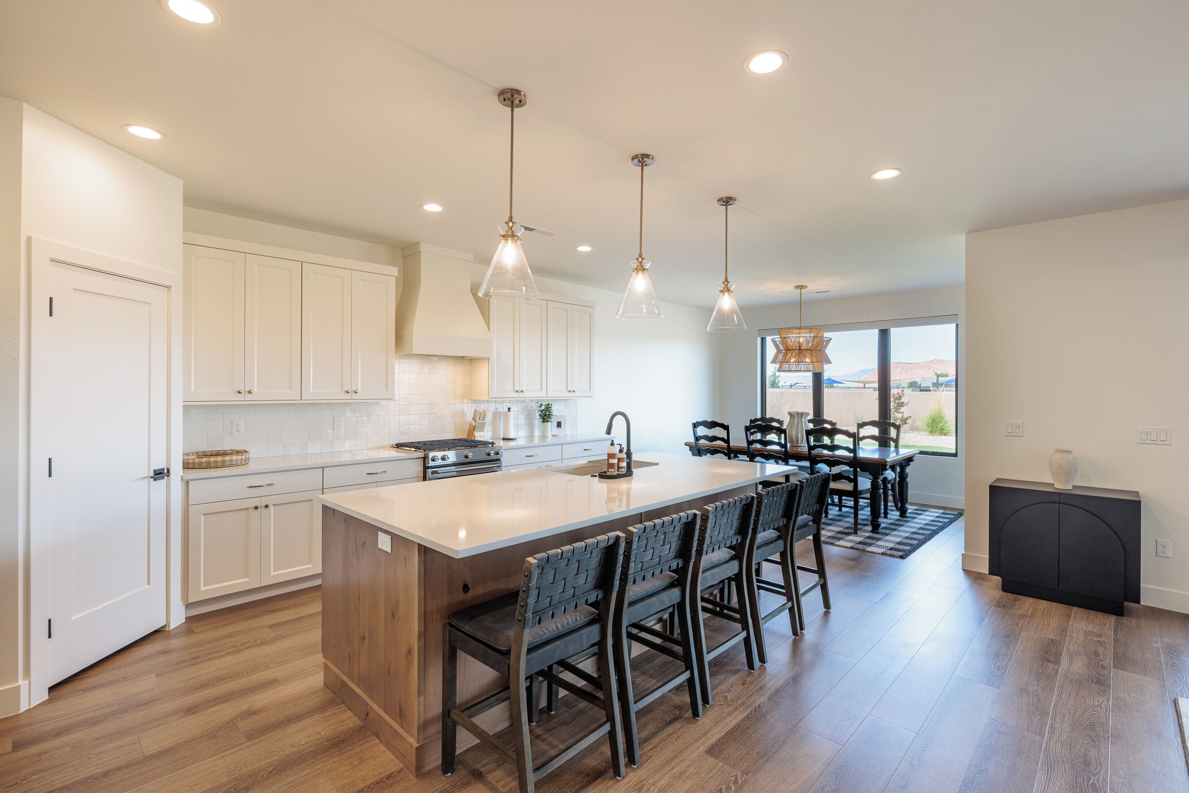Una cocina moderna con una isla central, iluminación colgante y vistas al exterior.