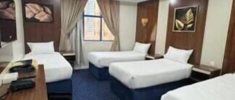 A hotel room with two single beds, a desk, and a window.