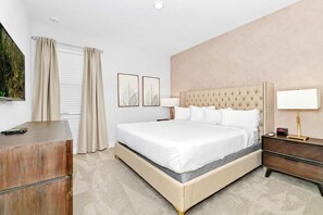 Ein Hotelzimmer mit einem großen Bett, Nachttischen, einem Flachbildfernseher und einem Fenster mit Vorhängen.