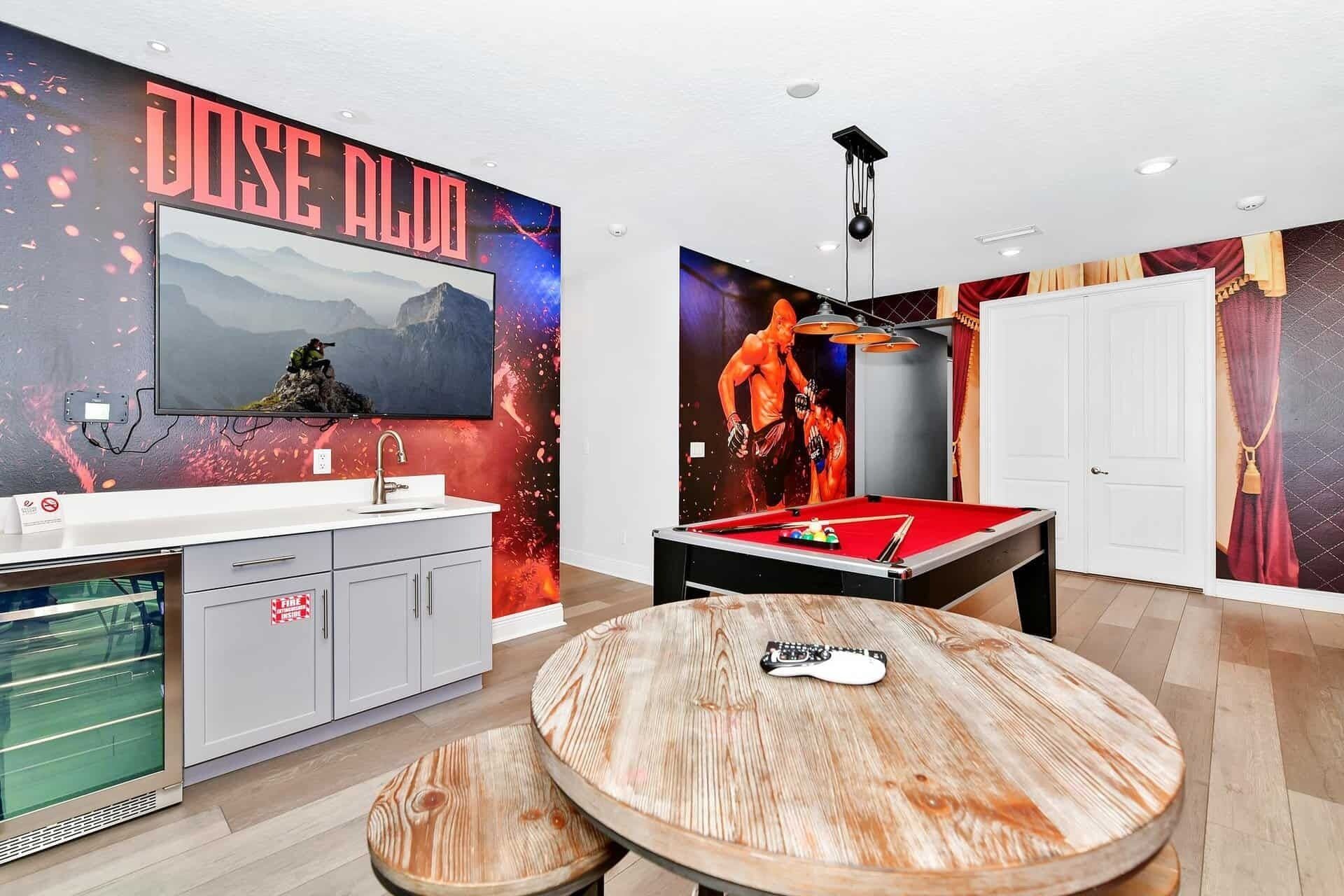 Ein Zimmer mit Billardtisch, einem an der Wand befestigten Fernseher und einer Wand mit dem Schriftzug 'DOSE ALDO'.