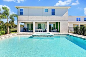 Une maison à deux étages avec une piscine, un espace salon extérieur et une cour clôturée.