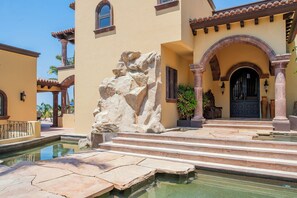 A building with a pool, stone steps, and a door with an archway. - Stunning 8BR Cabo Villa with Butler & Cooking Services (Cabo San Lucas)