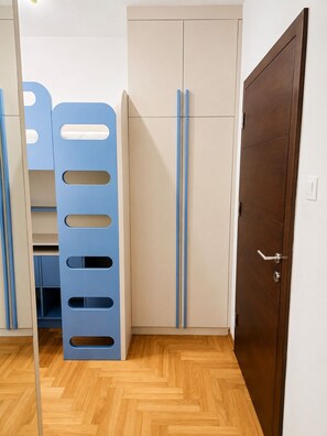Une chambre avec un lit superposé, une armoire et une porte.