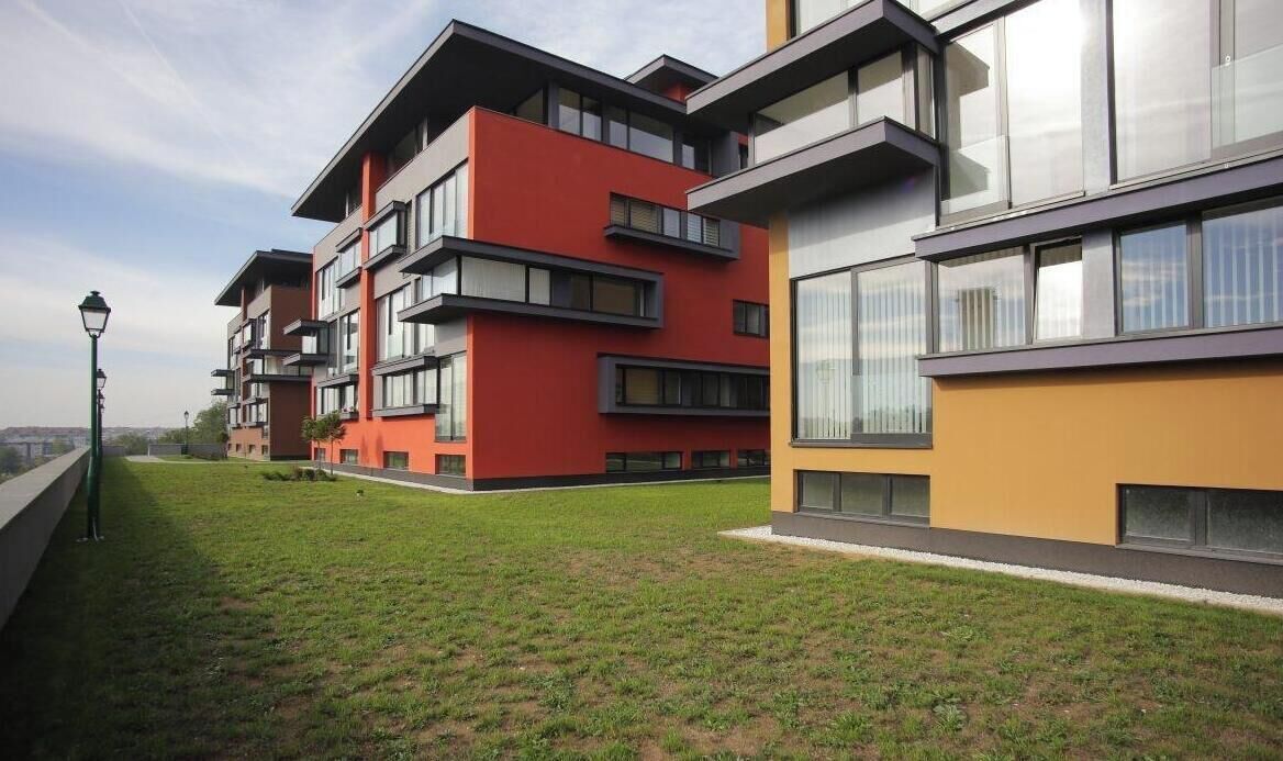 A modern apartment complex with multiple balconies, large windows, and a well-maintained lawn.