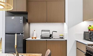 Eine moderne Küche mit integriertem Mikrowellenherd, einem Edelstahl-Kühlschrank und Holzschränken.