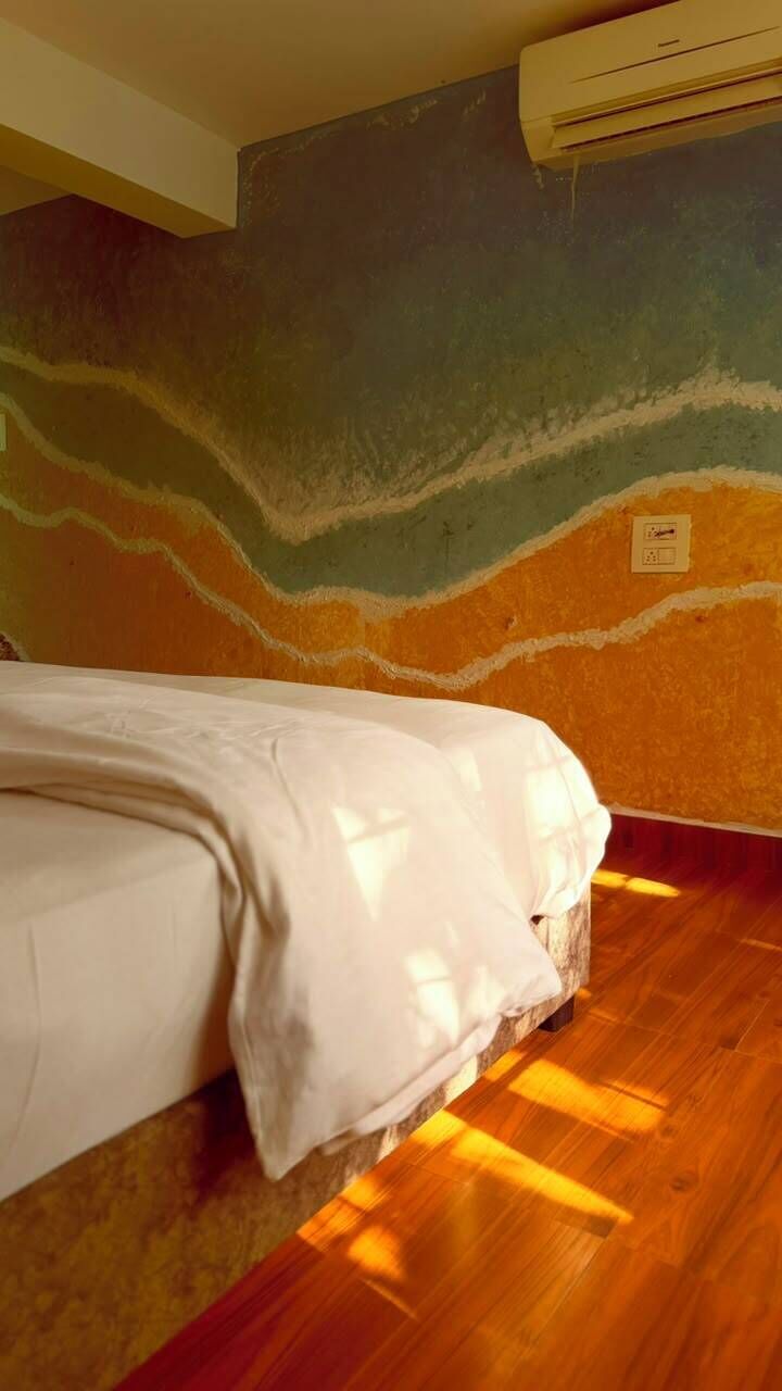 Una habitación con cama, suelo de madera y un diseño pintado en la pared.