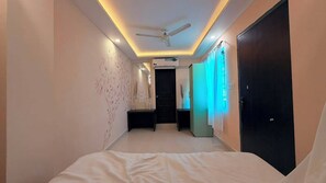 A hotel room with a bed, a ceiling fan, a door, and a wall with a decorative pattern.