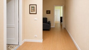 Um corredor com sofá, quadros nas paredes e uma porta que dá para outro quarto.